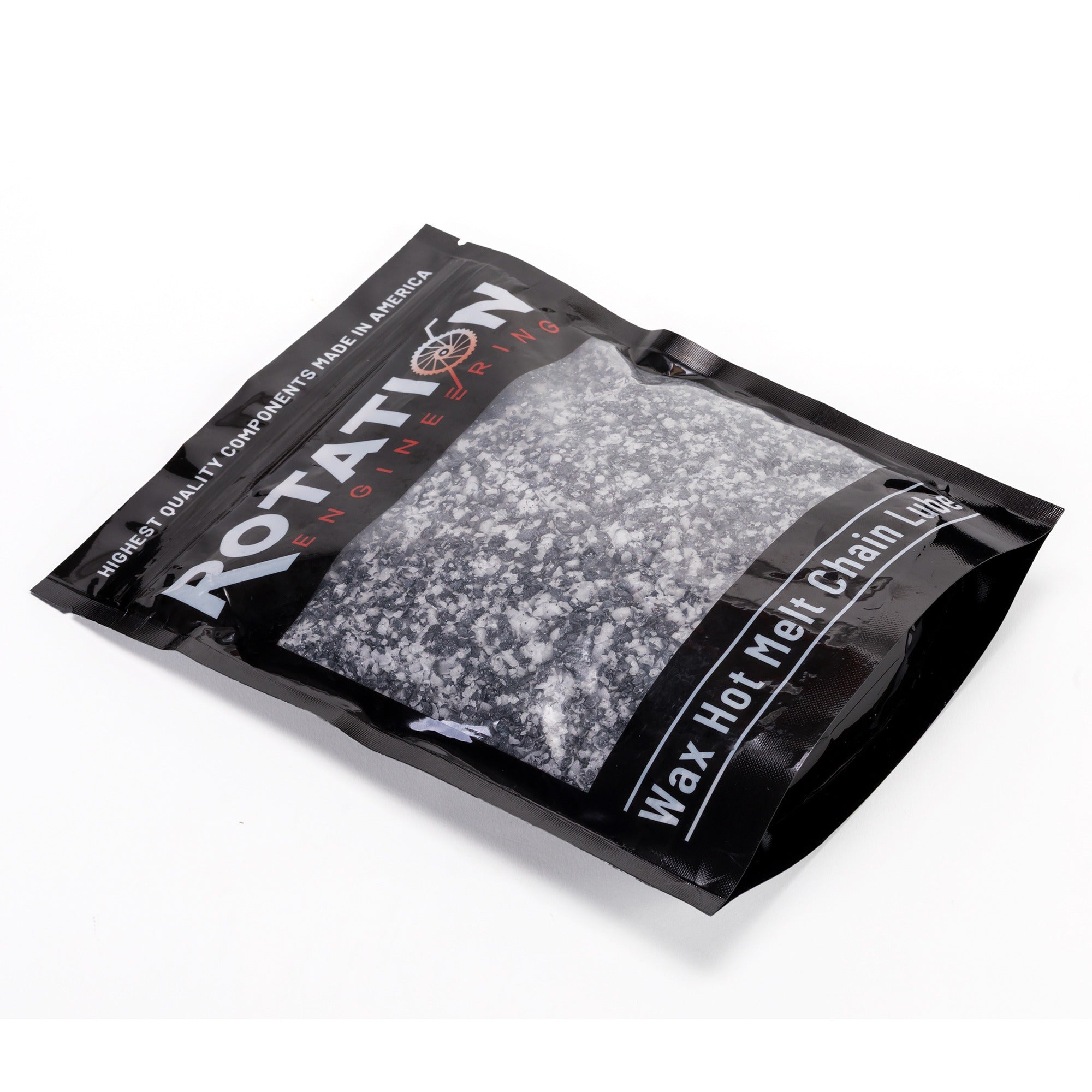 Black pouch labeled "Rotation Engineering" containing wax hot melt chain lube. The pouch displays white granular contents. Industrial and professional tone.